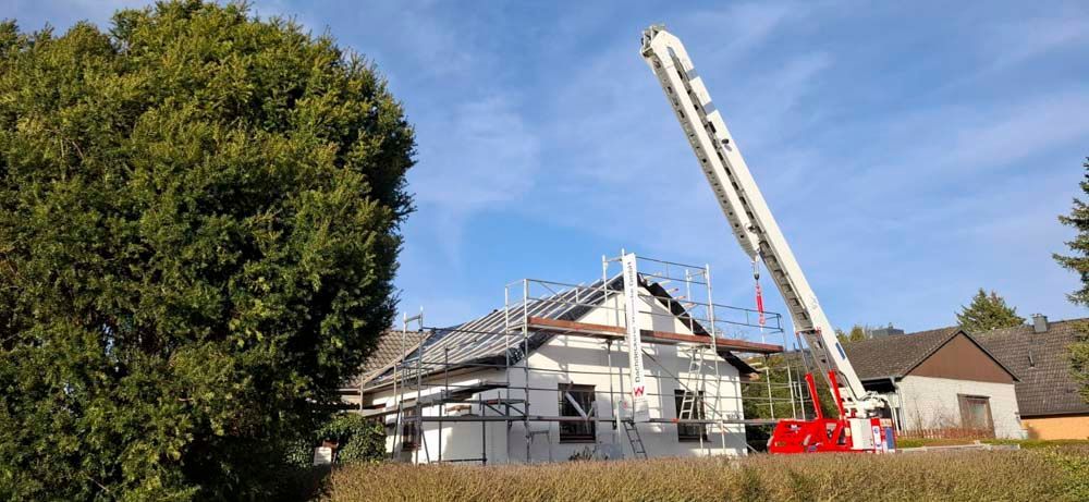 Ein Kran hebt das Dach eines im Bau befindlichen Hauses an.