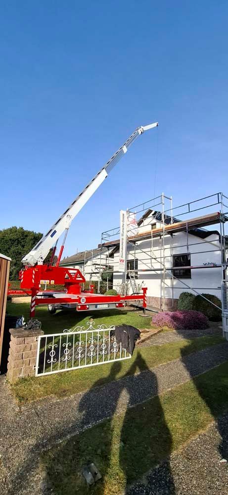 Ein rot-weißer Kranich sitzt vor einem Haus.