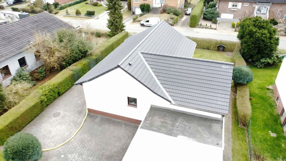 Eine Luftaufnahme eines Hauses mit grauem Dach in einem Wohngebiet.