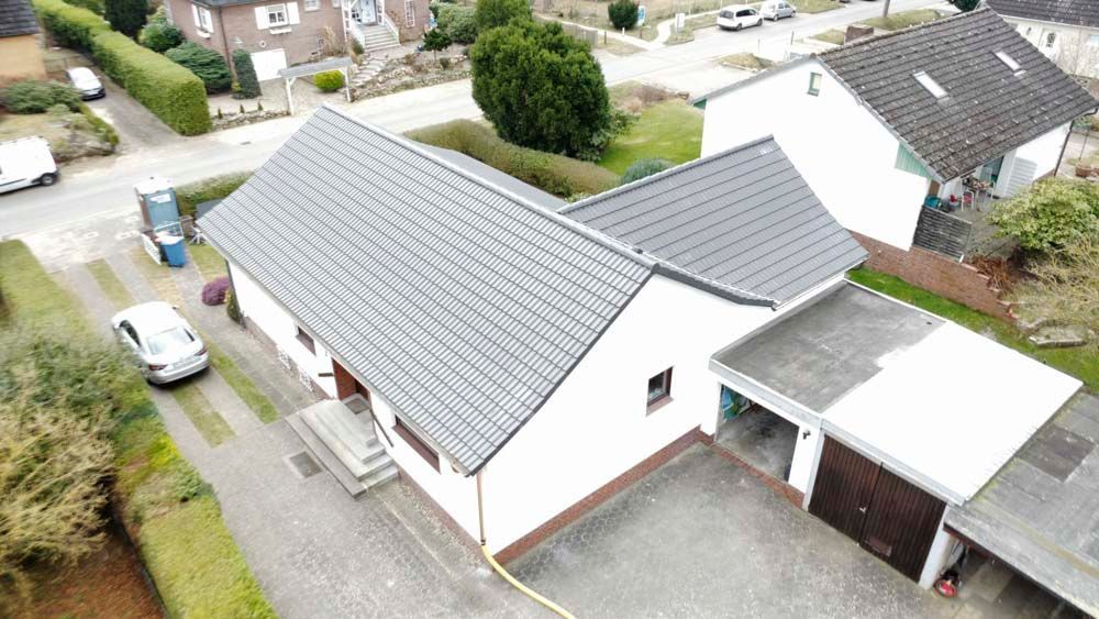 Eine Luftaufnahme eines Hauses mit grauem Dach in einem Wohngebiet.