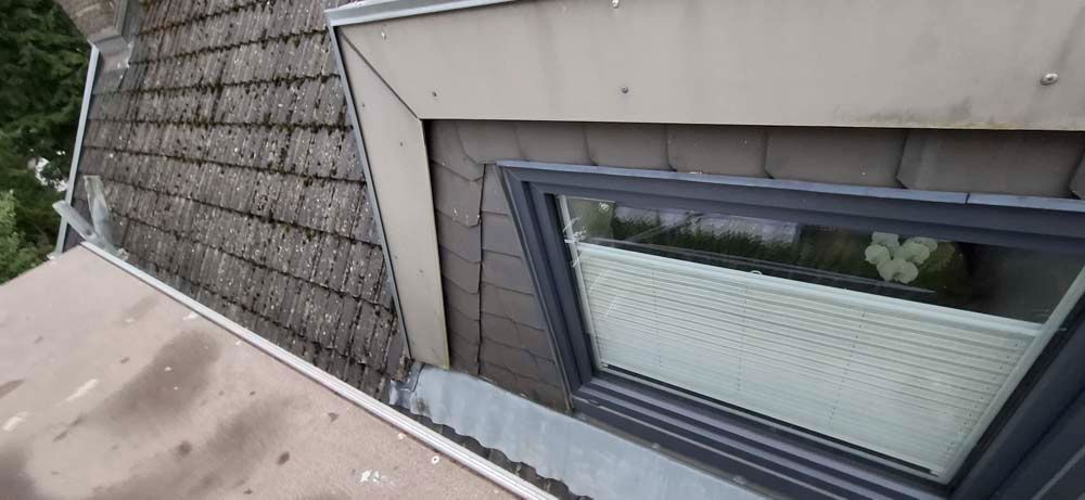 Ein Fenster an der Seite eines Gebäudes mit einem Dach im Hintergrund.