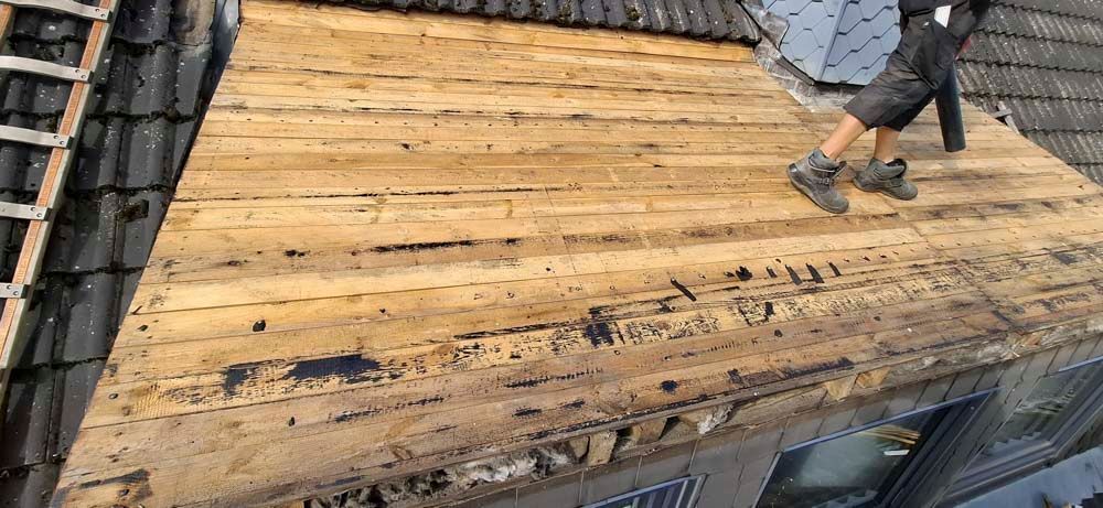 Ein Fenster an der Seite eines Gebäudes mit einem Dach im Hintergrund.