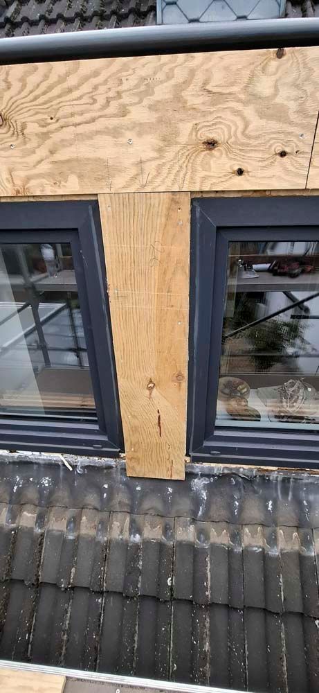 Auf dem Dach eines Gebäudes werden zwei Fenster eingebaut.