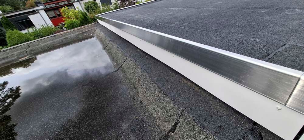 Eine Nahaufnahme eines Dachs mit einer Metallverkleidung und einer Wasserpfütze.