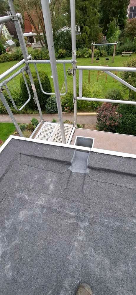 Eine Person steht auf einem Gerüst auf einem Dach.