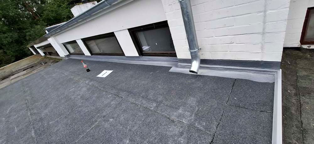 An der Seite eines Gebäudes wird ein schwarzes Dach angebracht.