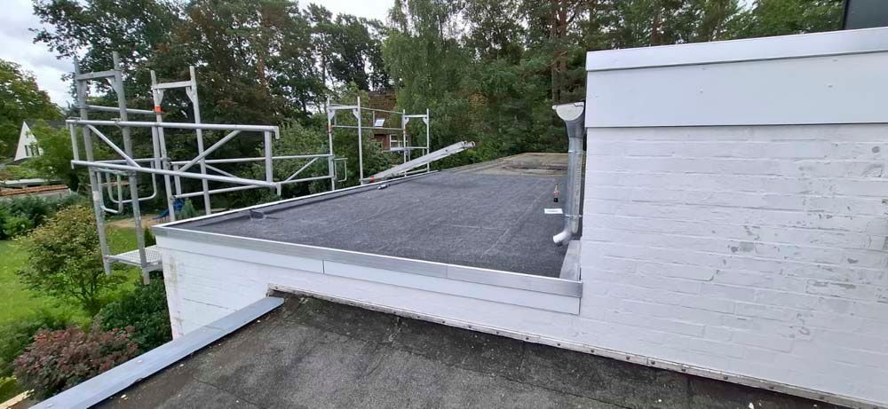 Ein Dach mit einem Gerüst darauf und Bäumen im Hintergrund.