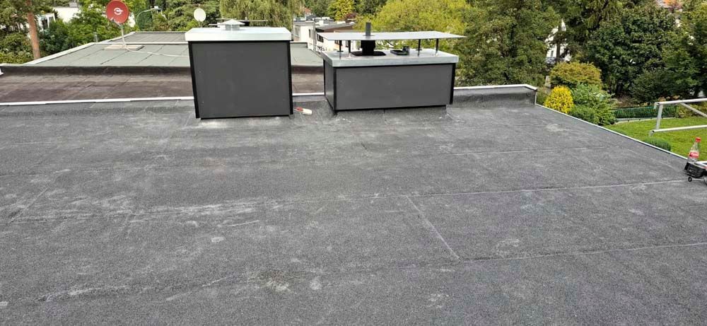 Auf dem Dach eines Gebäudes befinden sich zwei Schornsteine.