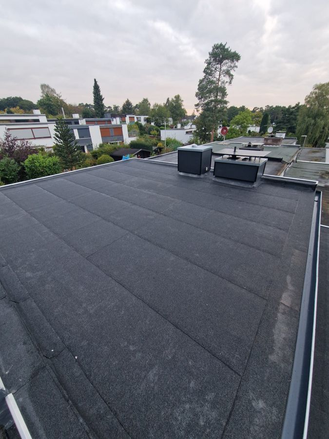 Ein schwarzes Dach mit ein paar Bäumen im Hintergrund