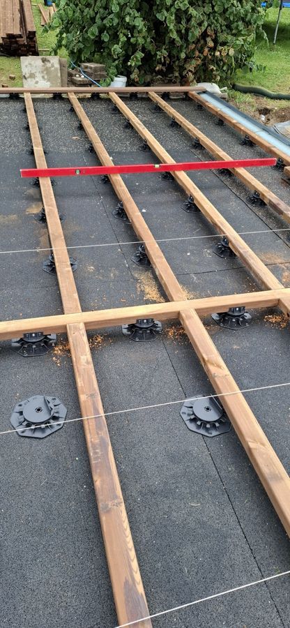 Es wird ein Holzdeck gebaut, auf dem sich eine rote Wasserwaage befindet.