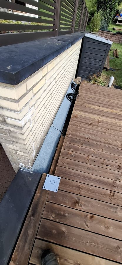 Neben einer Backsteinmauer befindet sich ein Holzdeck.