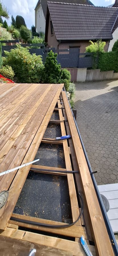 Vor einem Haus wird eine Holzterrasse gebaut.