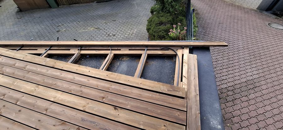 Auf einem gepflasterten Gehweg wird ein Holzdeck gebaut.