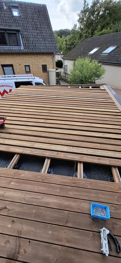 Auf dem Dach eines Hauses wird eine Holzterrasse gebaut.