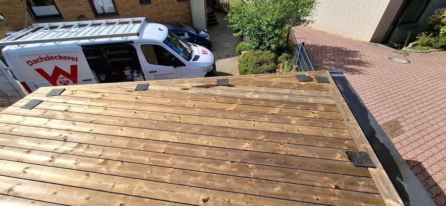 Ein weißer Lieferwagen mit dem Buchstaben W an der Seite ist auf einem Holzdeck geparkt.