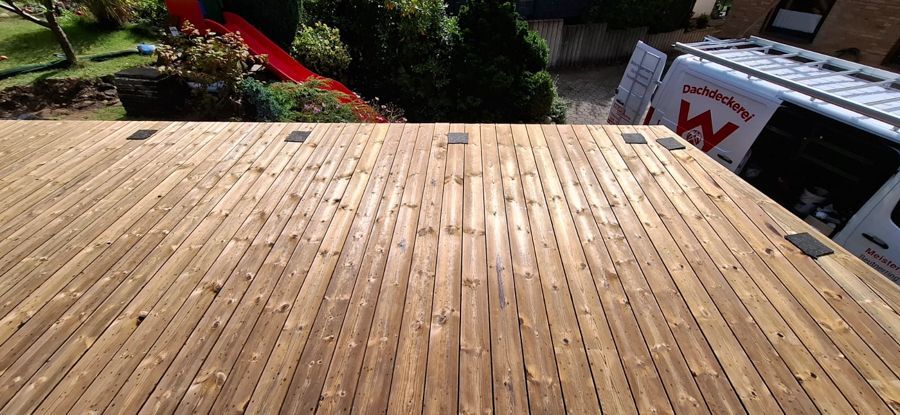 Ein Holzdeck mit einem weißen Lieferwagen im Hintergrund.