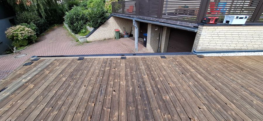 Ein Holzdeck mit einem Backsteingebäude im Hintergrund.