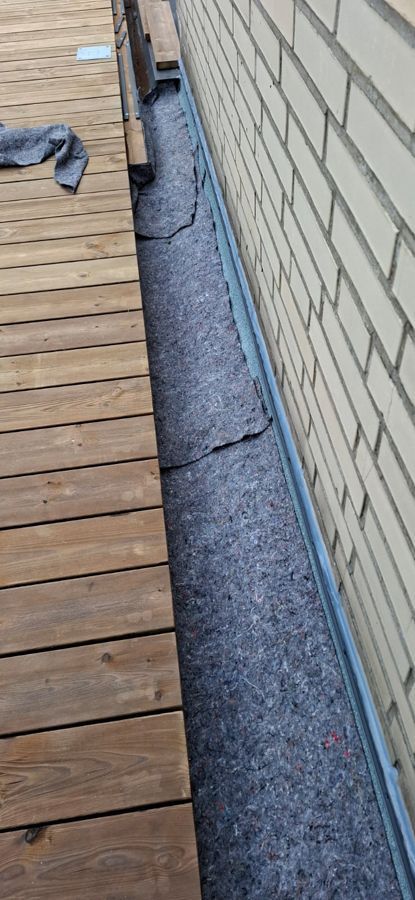 Neben einer Backsteinmauer steht ein Holzdeck.