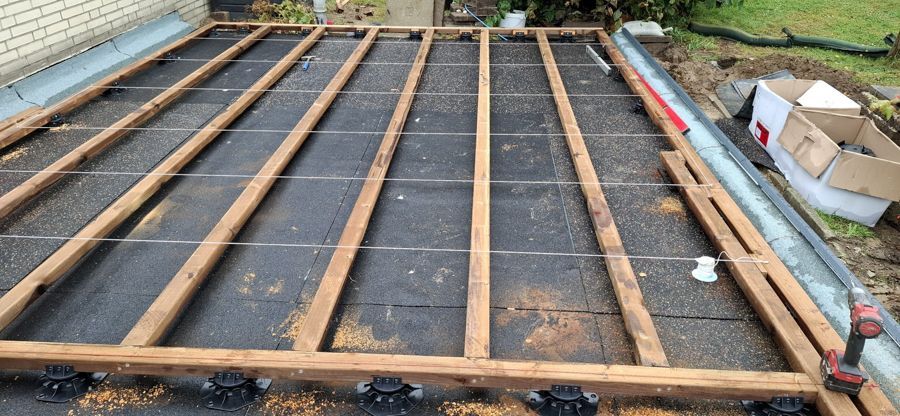 Auf einem Betonboden wird ein Holzdeck errichtet.