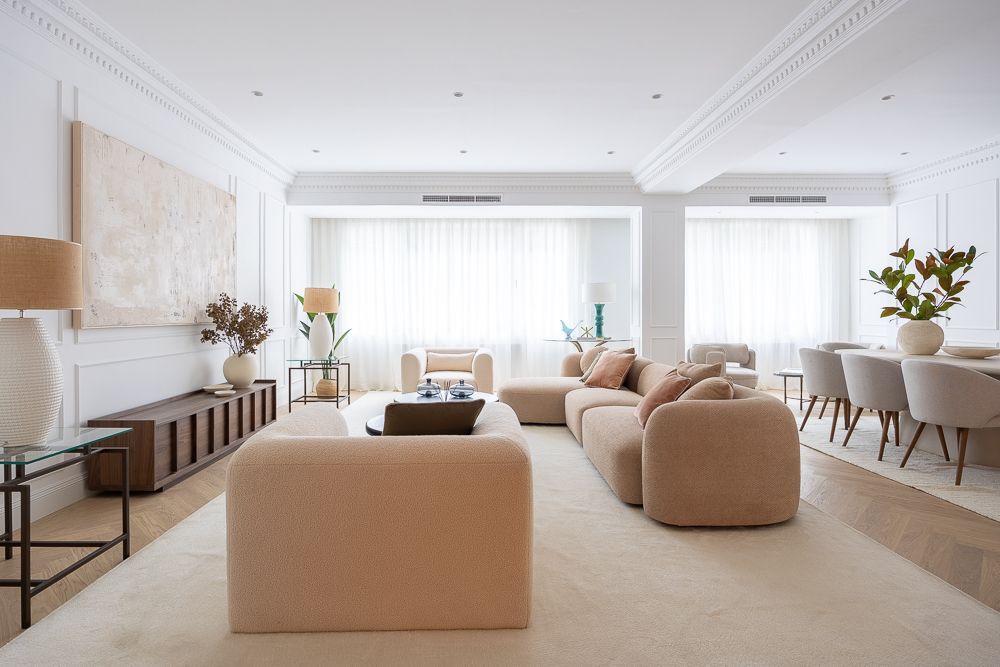 Salón con muebles color beige, tonos neutros y molduras decorativas.