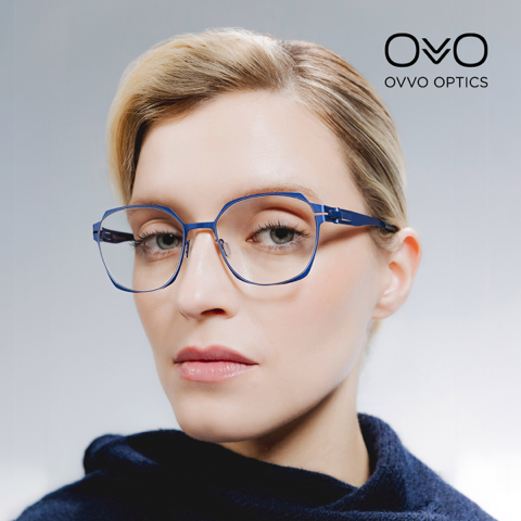 Frau mit blau-silberner geometrischer Brille, die den Betrachter anblickt. „OVVO Optics“-Logo in der Ecke.