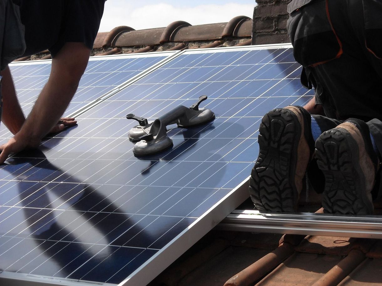 Dos hombres trabajando en un tejado mientras instalan placas solares