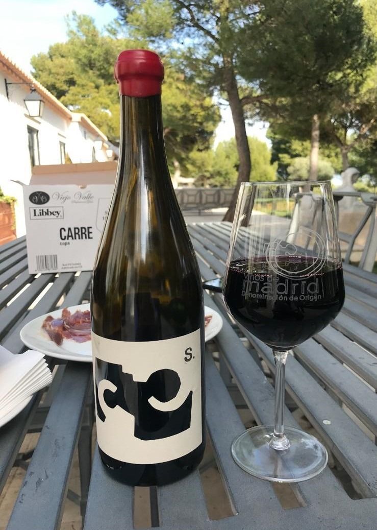 Una botella de vino reposa sobre una mesa junto a una copa de vino.