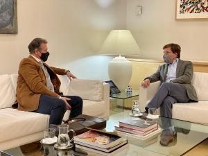 Dos hombres están sentados en sofás en una sala de estar hablando entre sí.