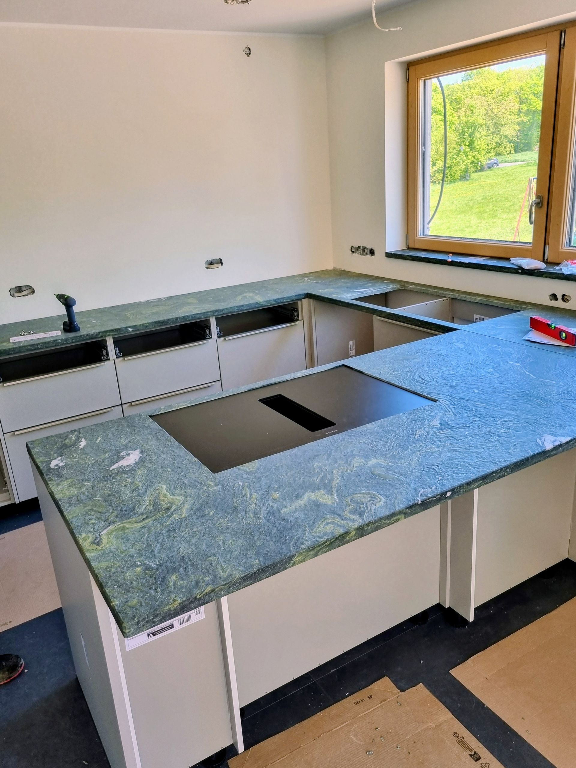 Küchenarbeitsplatte aus Naturstein in U-Form mit Fensterblick und maßgefertigter Montage