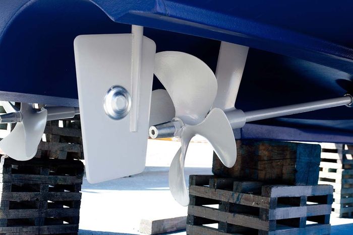 Primer plano de una hélice blanca montada debajo del casco azul de una embarcación sobre un remolque