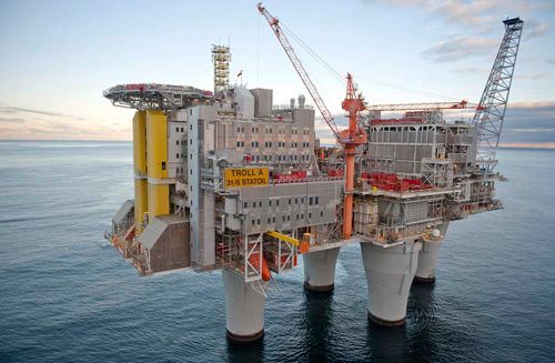 Plataforma petrolífera en alta mar, con grúas y estructuras amarillas sobre aguas tranquilas del océano