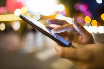 Eine Person hält ein Mobiltelefon in der Hand.