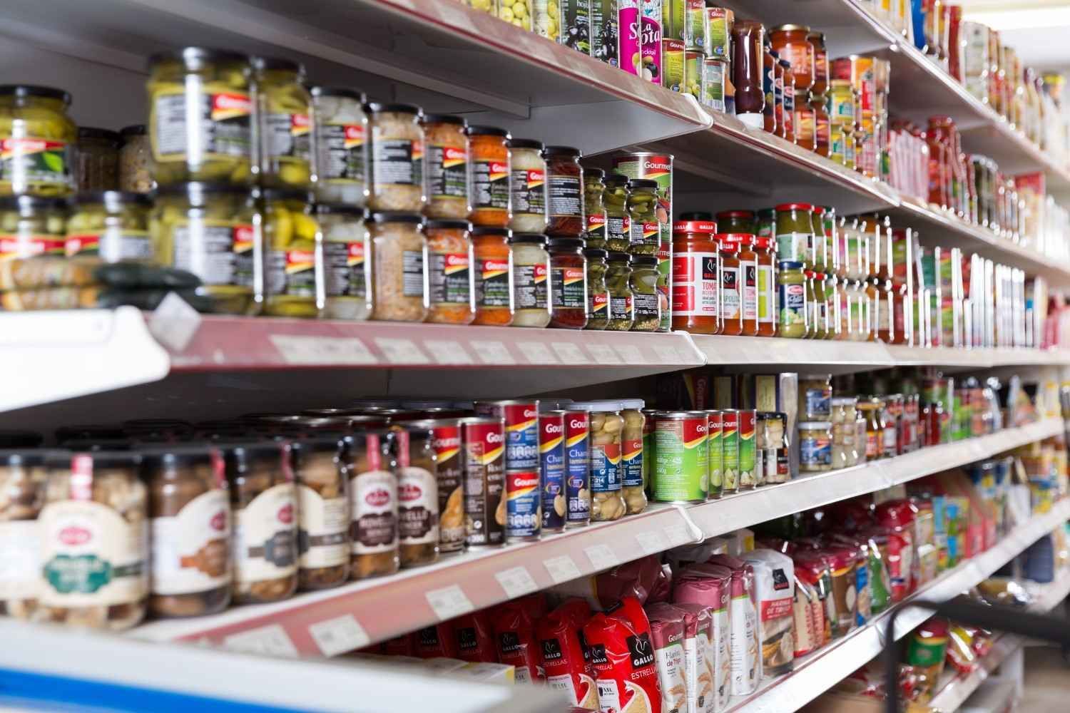 Estantes de un supermercado repletos de frascos de pepinillos, conservas y otros productos básicos de despensa.