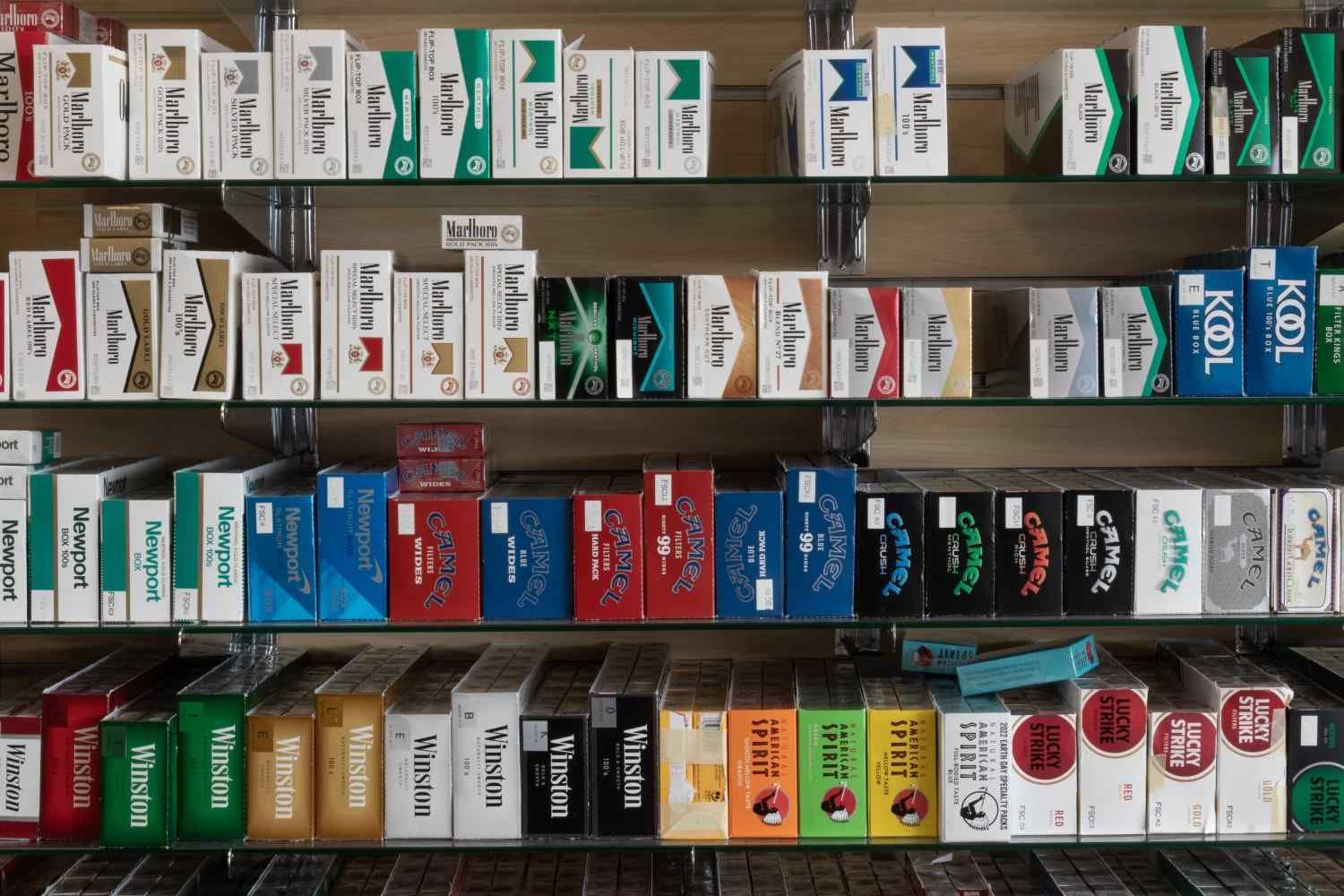 Estanterías que exhiben diversas marcas y coloridos paquetes de cigarrillos en un entorno de tienda minorista.