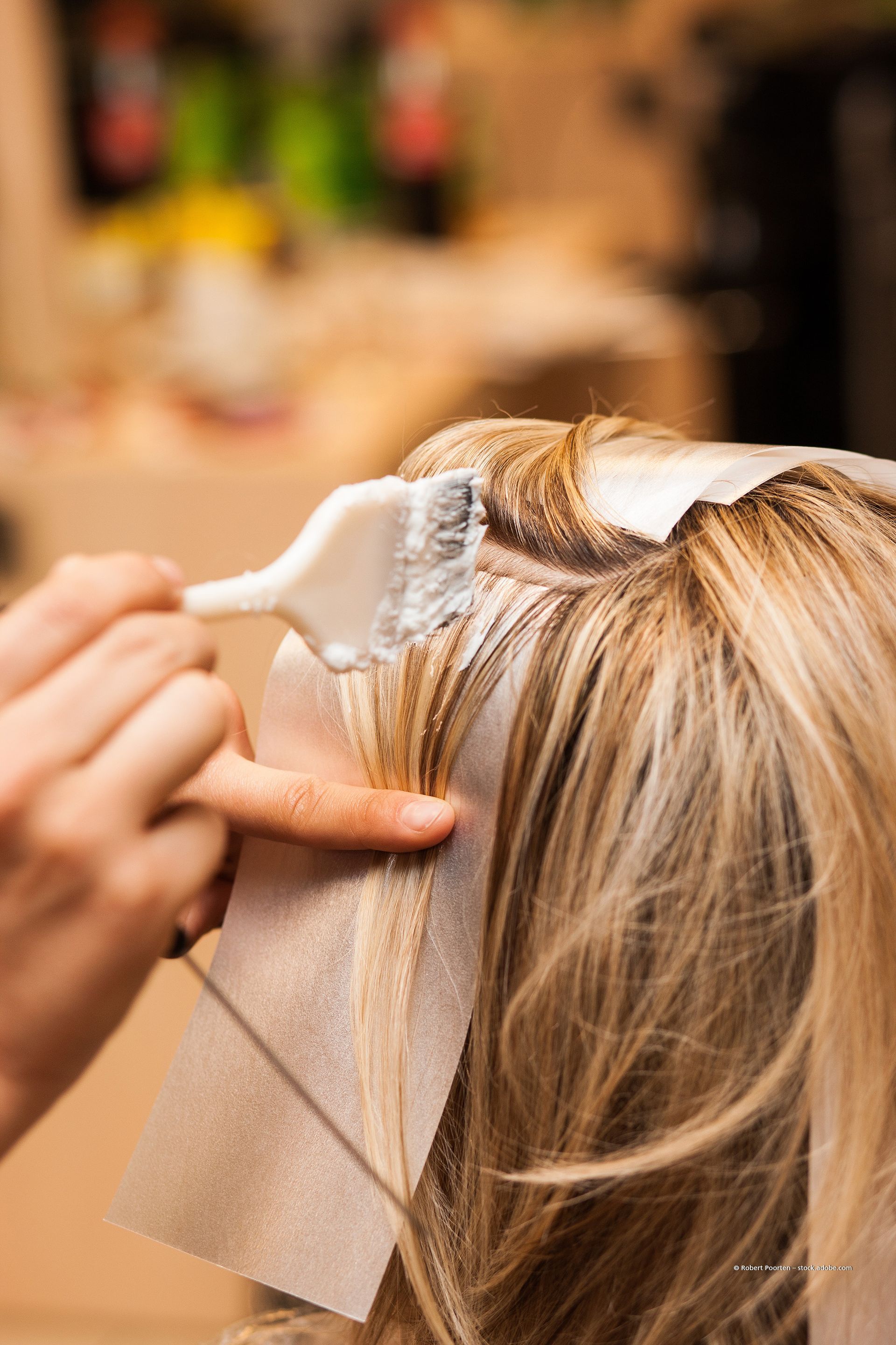 Friseurin befestigt in einem Salon blonde Haarverlängerungen mit Clips.