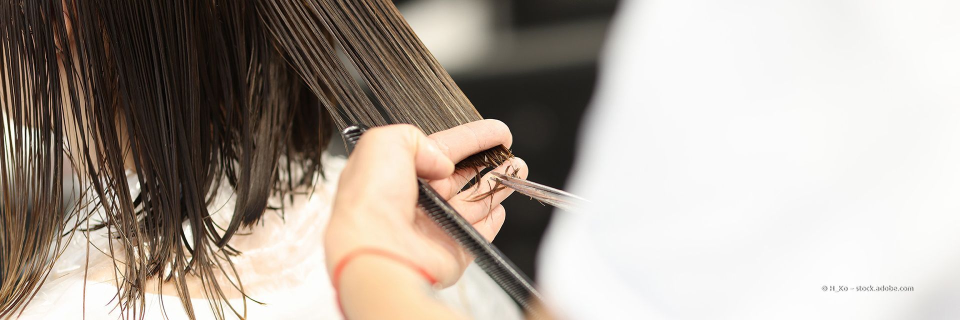 Friseurin schneidet einer Kundin im Salon mit Schere und Kamm die Haare.