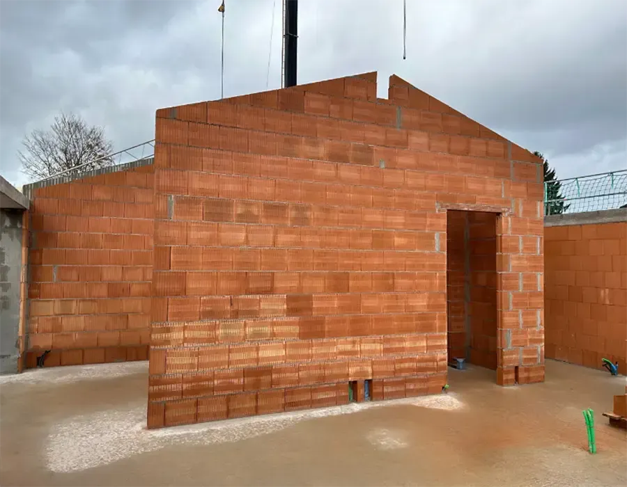 Außenwand eines Neubaus aus Ziegelmauerwerk während der Rohbauphase.