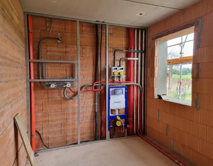 Installationswand im Neubau mit verlegten Wasser- und Heizungsleitungen im Rohbauzustand.