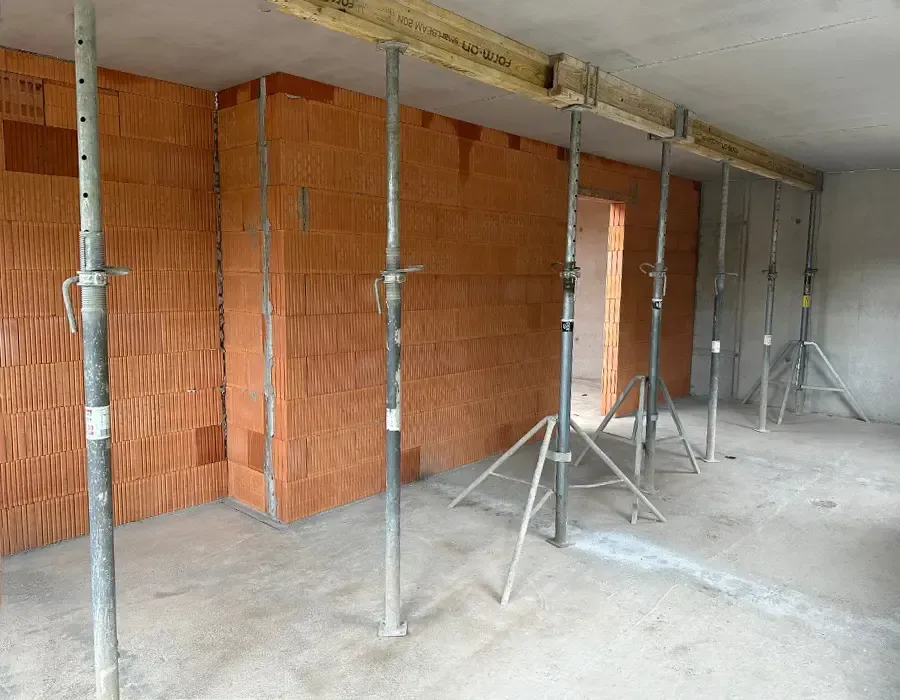 Rohbau-Innenraum mit Ziegelwänden und Deckenabstützung während der Bauarbeiten.