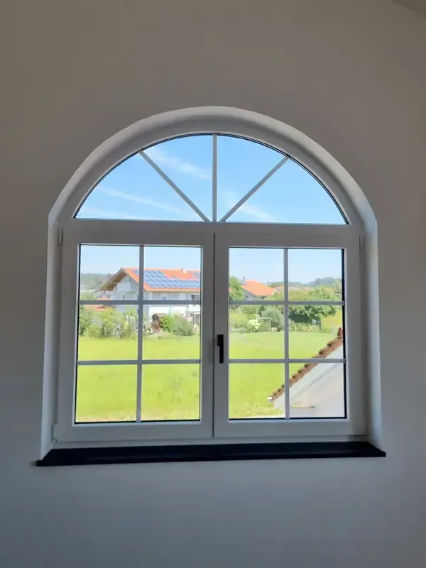 Rundbogenfenster im Innenbereich eines Neubaus mit Blick auf den blauen Himmel.
