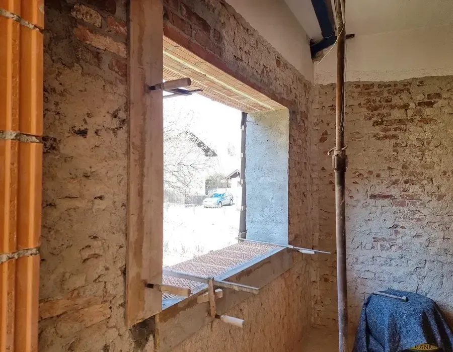 Innenraum mit neu geschaffener Fensteröffnung und freigelegtem Mauerwerk während der Sanierung.