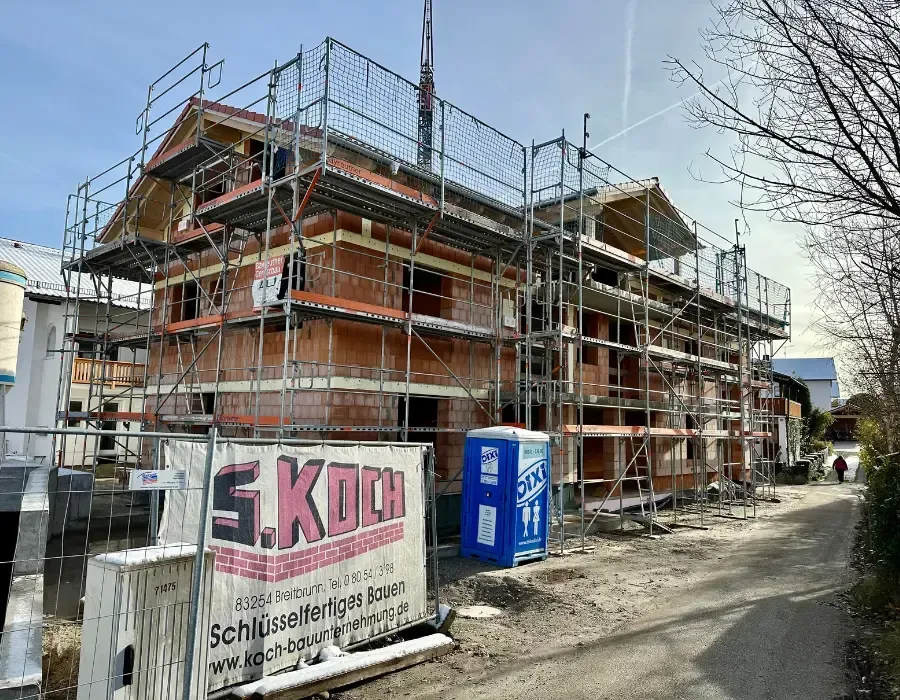 Mehrgeschossiger Neubau im Rohbau mit Gerüst und Mauerwerk während der Bauphase.
