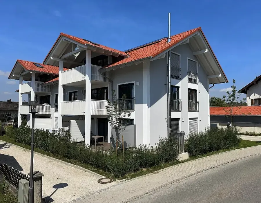 Modernes Mehrfamilienhaus mit Balkonen und rotem Satteldach