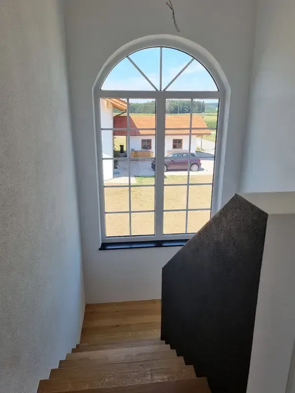 Fertiggestellter Wohnraum mit Rundbogenfenster und Blick ins Freie.