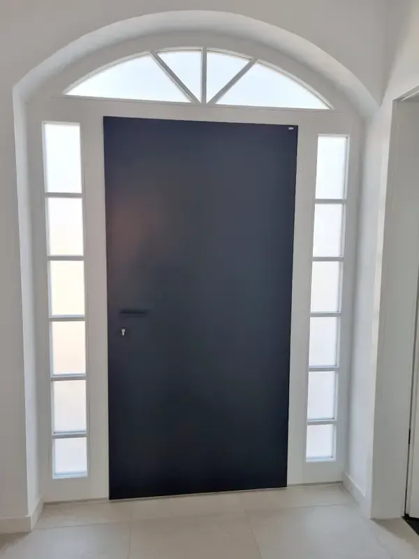 Fertiggestellter Eingangsbereich eines Wohnhauses mit moderner Haustür und Rundbogenfenster.