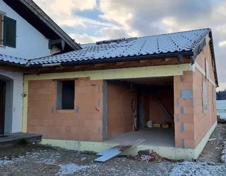 Neuer Anbau im Rohbauzustand mit Ziegelmauerwerk und teilweise fertiggestelltem Dach.