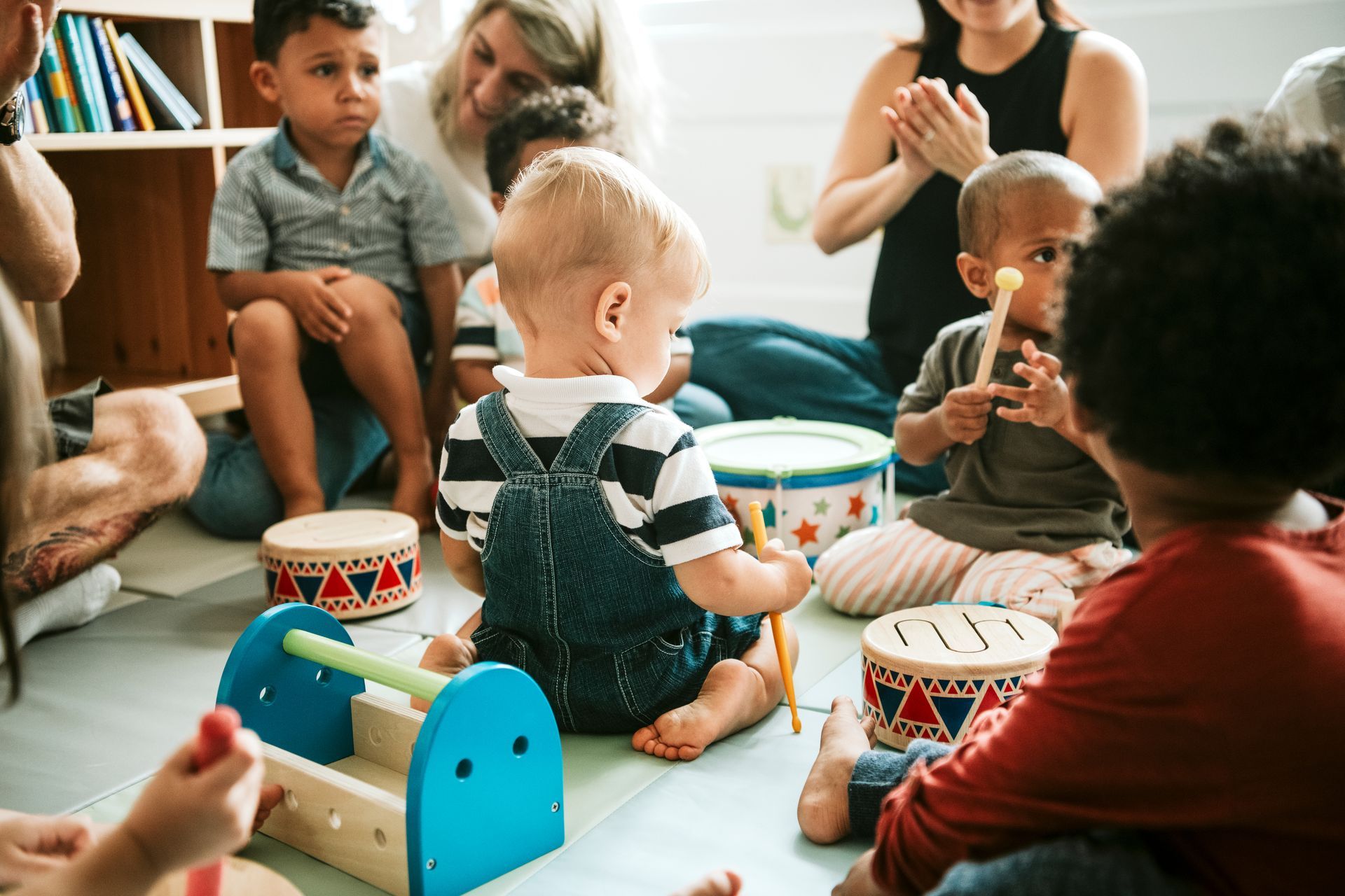 Un gruppo di bambini è seduto sul pavimento e suona la batteria.