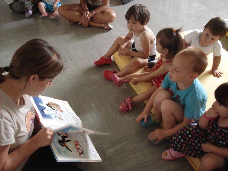 Una donna sta leggendo un libro a un gruppo di bambini