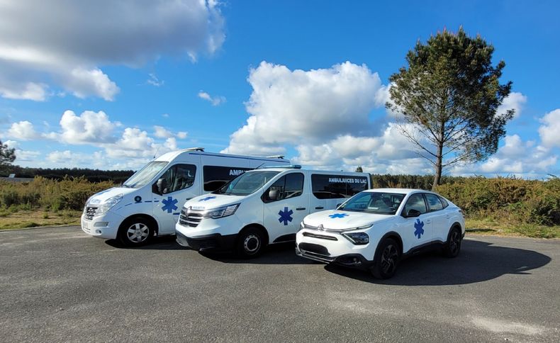 Trois véhicules de secours sont stationnés sur un parking goudronné.