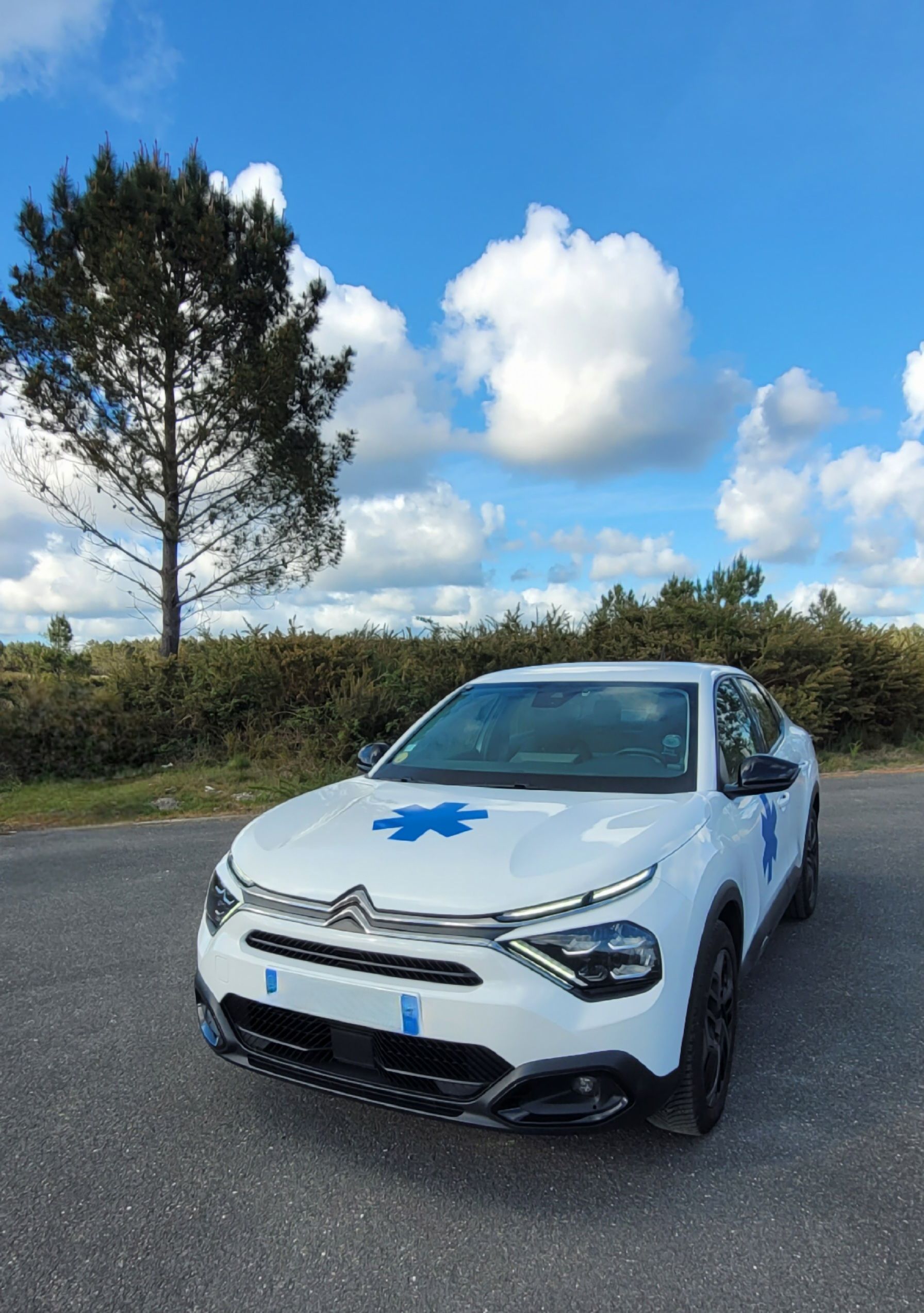 Une Citroën avec l'emblème, garée sur une route asphaltée.